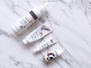 Flat lay of Glossier beauty products on marble background